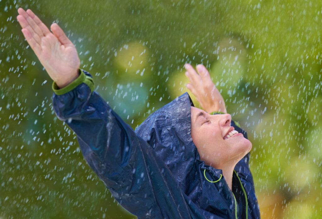 Dancing in the rain. Cropped shot of a young woman dressed in a raincoat enjoying the rain
